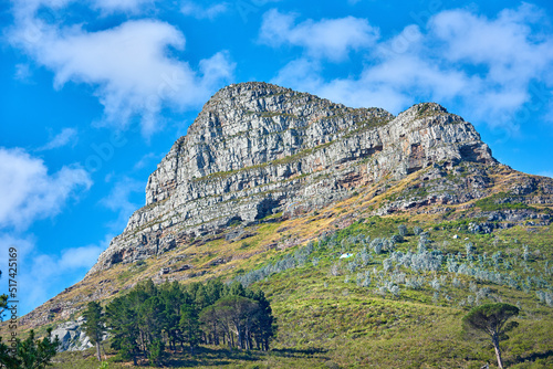 Landscape of a mountain on cloudy blue sky with copy space. Beautiful nature view of Lions Head mountains peak with lush green trees and bushes in a popular hiking location in Cape Town, South Africa