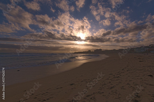 puesta de sol contra el sol en la playa con nubes en el horizonte photo