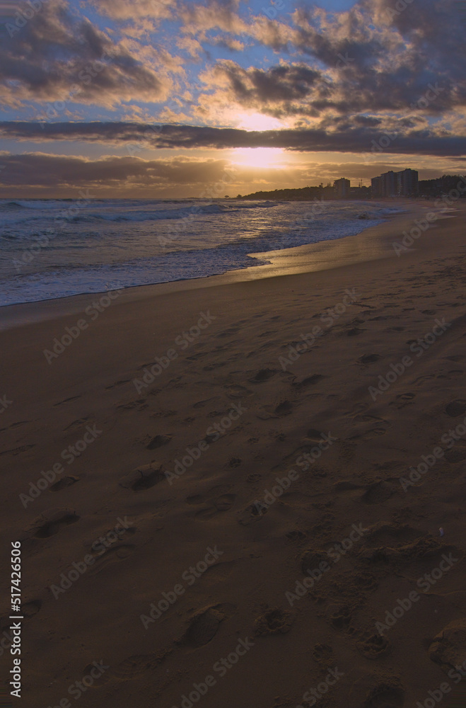 puesta de sol en la orilla de la playa con ciudad de fondo, lente gran angular