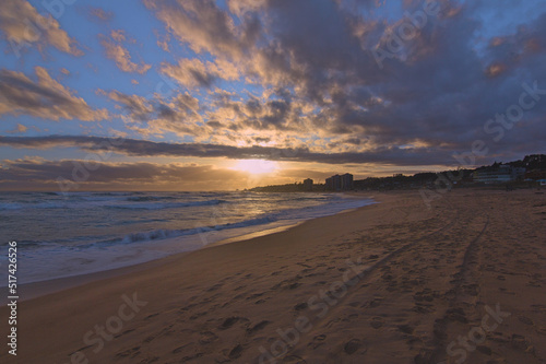 puesta de sol en la orilla de la playa con ciudad de fondo, lente gran angular