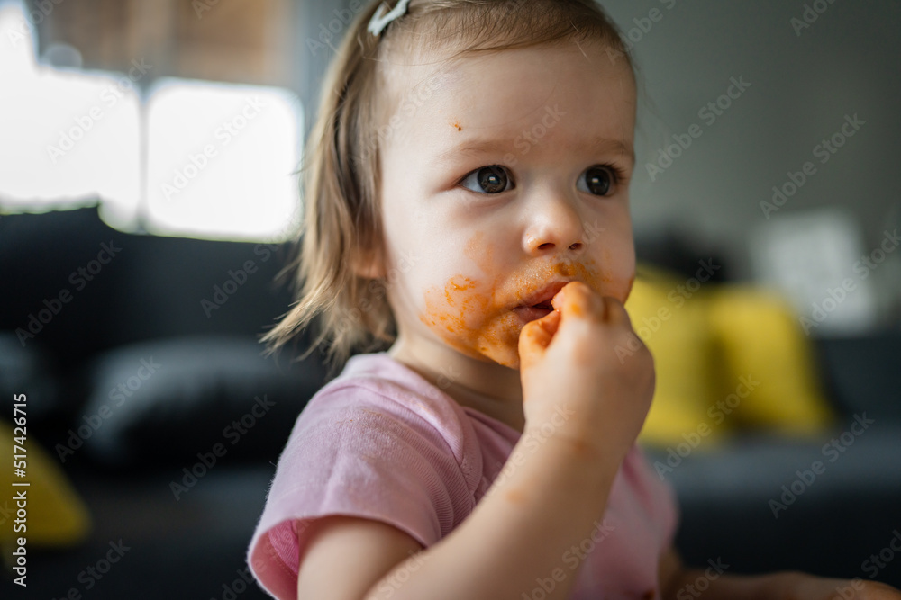one girl small caucasian toddler female child daughter eating alone at the table at home while watching tv making mess on her face dirty sauce childhood growing up development concept copy space one girl small caucasian toddler female child daughter eating alone at the table at home while watching tv making mess on her face dirty sauce childhood growing up development concept copy space