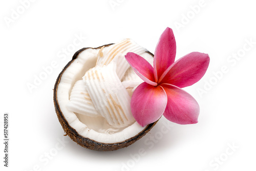 Half cut coconut and frangipani flower on white.