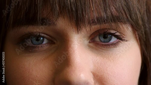 Closeup of a woman with blue eyes on dark studio background. An aware humanitarian volunteer or justice activist looking at the camera with concerned, serious look on her face and sincere expression photo