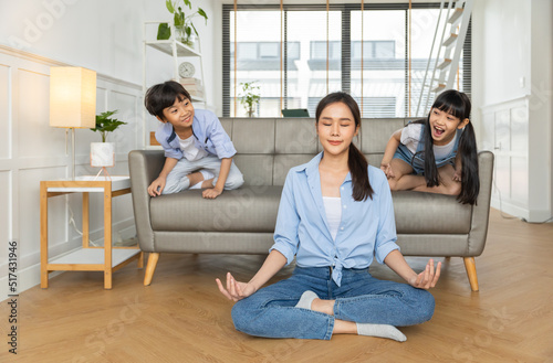Asian woman with cute funny kid daughter doing yoga exercise at home.Friendly sincere two female generations family relaxing on couch, healthcare concept.