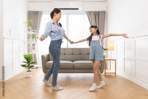 Happy asian family mother father and daughter dancing at home in living room.