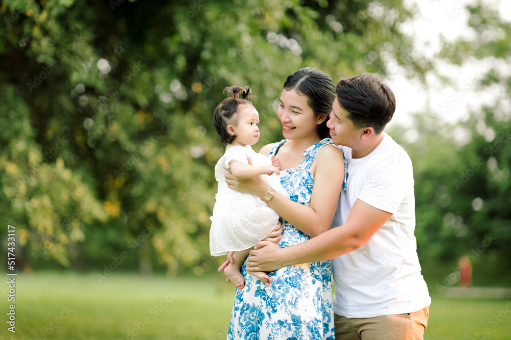 Happy Asian family father, mother, and little child daughter playing in the park enjoying the beautiful nature at sunset, Happy family holidays concept. Happy Asian family father, mother, and little child daughter playing in the park enjoying the beautiful nature at sunset, Happy family holidays concept.