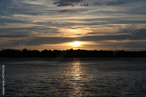 The sun sets across the river on a peaceful evening
