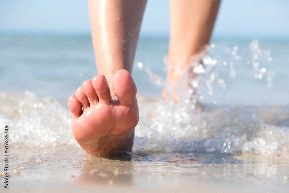 woman walking to sea and beach on a beautiful island Ocean foam wrapped around a girl's leg. Her legs touched the splashing water. Hit the skin on the legs and she walked in the soft sunshine morning