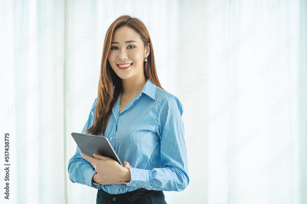 Charming Asian woman with a smile standing holding papers and mobile phone at the office. Charming Asian woman with a smile standing holding papers and mobile phone at the office.