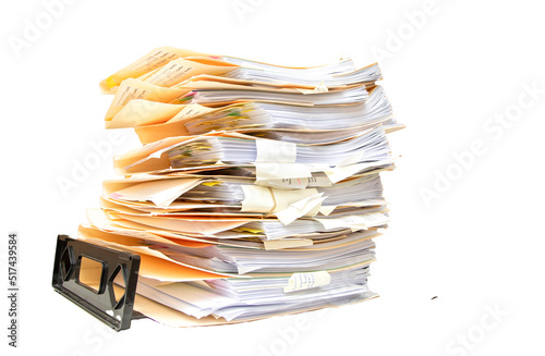 Manila folders stacked overflowing an in box at an office on a white background