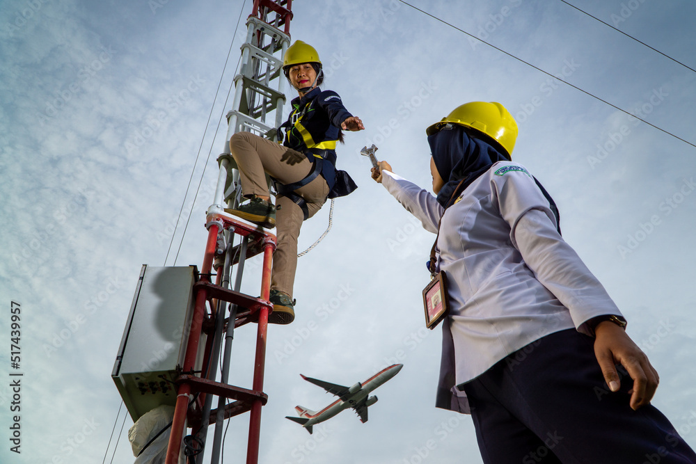 Fototapeta premium Badung, Bali, Dec 8th 2020: In a clearly day, 2 female technical workers repairing communication equipment at the airport. One of them is wearing a hijab
