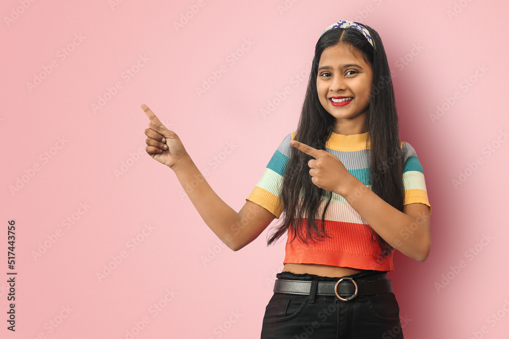 Close-up isolated portrait of charming cute adorable shine cheerful cheery Indian Asian girl pointing aside to a copy space. Close-up isolated portrait of charming cute adorable shine cheerful cheery Indian Asian girl pointing aside to a copy space.