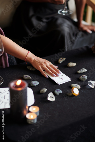 Young woman using tarot cards and rune stones for divination practice at home
