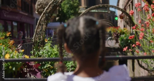 Biracial little girl playing and turning to see gigantic distant Catherdal in downtown Colmar, France photo
