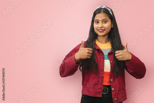 Isolated portrait of Smiling Indian Asian pretty young woman showing thumbs up with copy space.