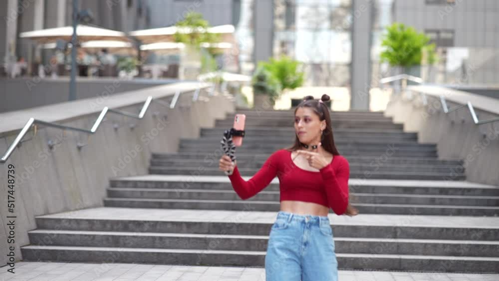Young female blogger with smartphone streaming on the street.