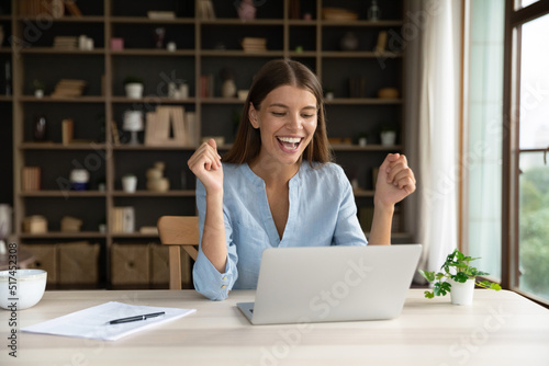Happy female office employee read pleasant e-mail on laptop, get career advancement, promoted, celebrate salary growth, receive fantastic news with sell-out, professional success, new software concept photo