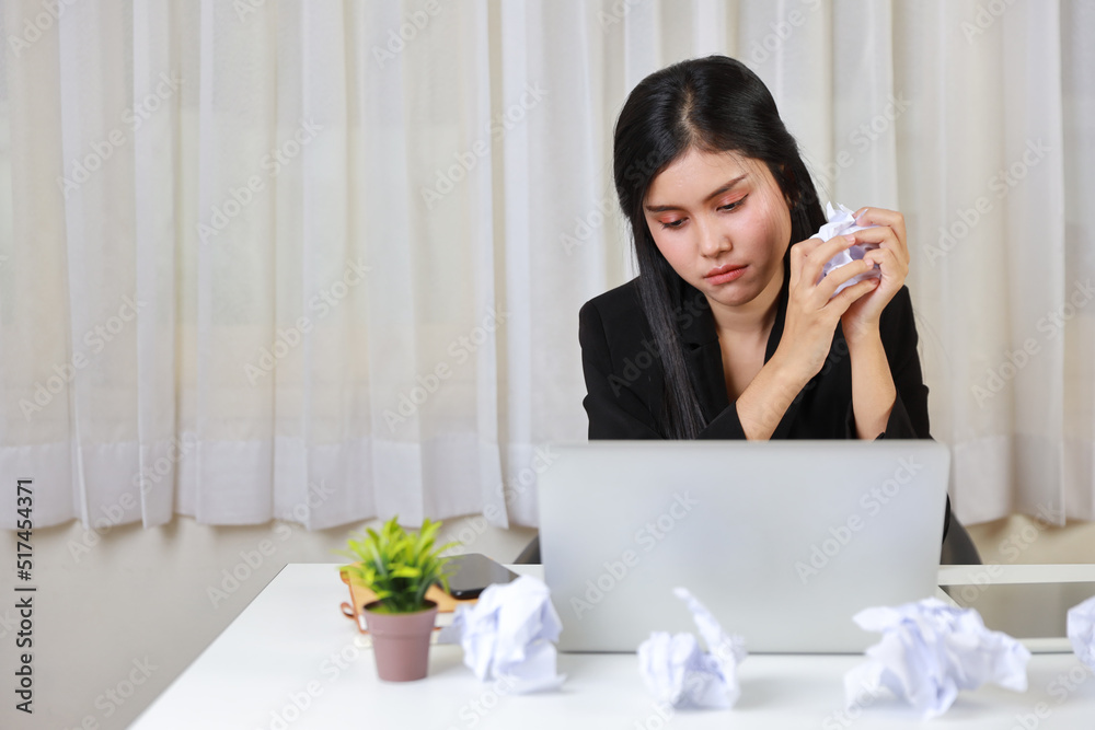 Mid adult businesswoman feeling upset after bad news business failure or get fired and feeling discouraged, distraught and hopeless on blue background with computer and crumpled paper Mid adult businesswoman feeling upset after bad news business failure or get fired and feeling discouraged, distraught and hopeless on blue background with computer and crumpled paper