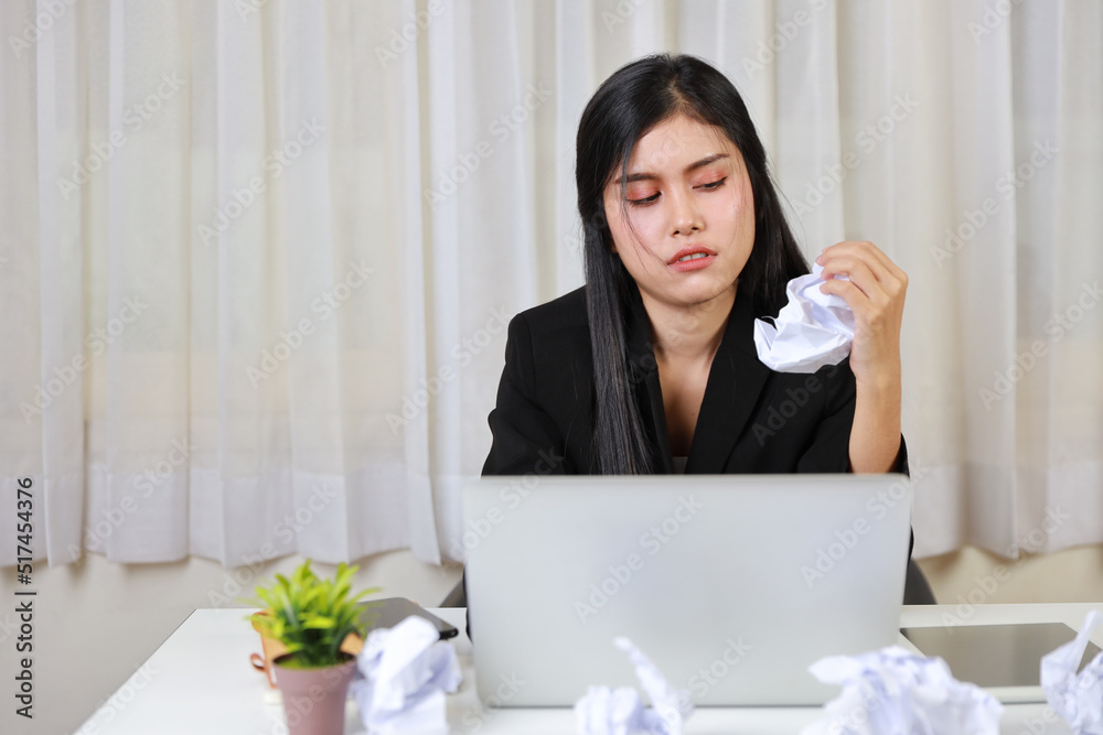 Mid adult businesswoman feeling upset after bad news business failure or get fired and feeling discouraged, distraught and hopeless on blue background with computer and crumpled paper Mid adult businesswoman feeling upset after bad news business failure or get fired and feeling discouraged, distraught and hopeless on blue background with computer and crumpled paper