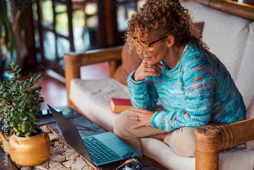Photography Side view of young woman using laptop sitting on the couch in indoor home leisure modern activity