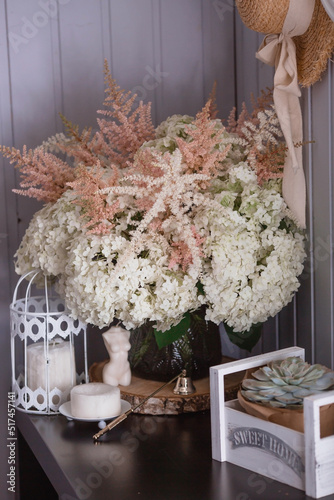 A succulent on a decorative bicycle and a bouquet of white hydrangeas and astilba. Interior in Provence style. A concept for a flower shop or home comfort and decor in the house.