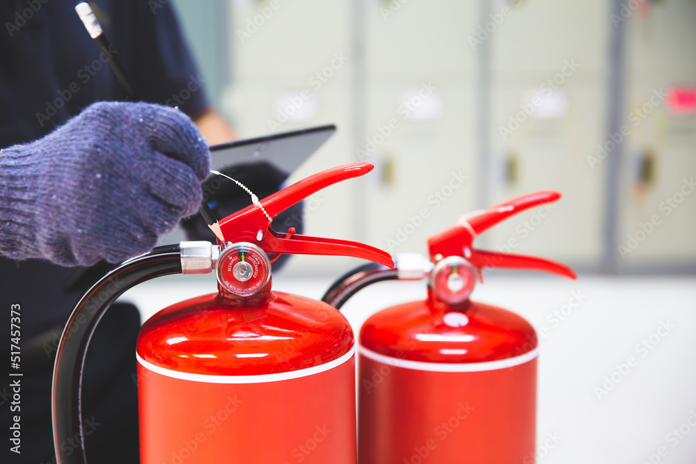 Obraz premium Fire extinguisher has hand engineer inspection checking pressure gauges to prepare fire equipment for protection and prevent in emergency case and safety or rescue and alarm system training concept.