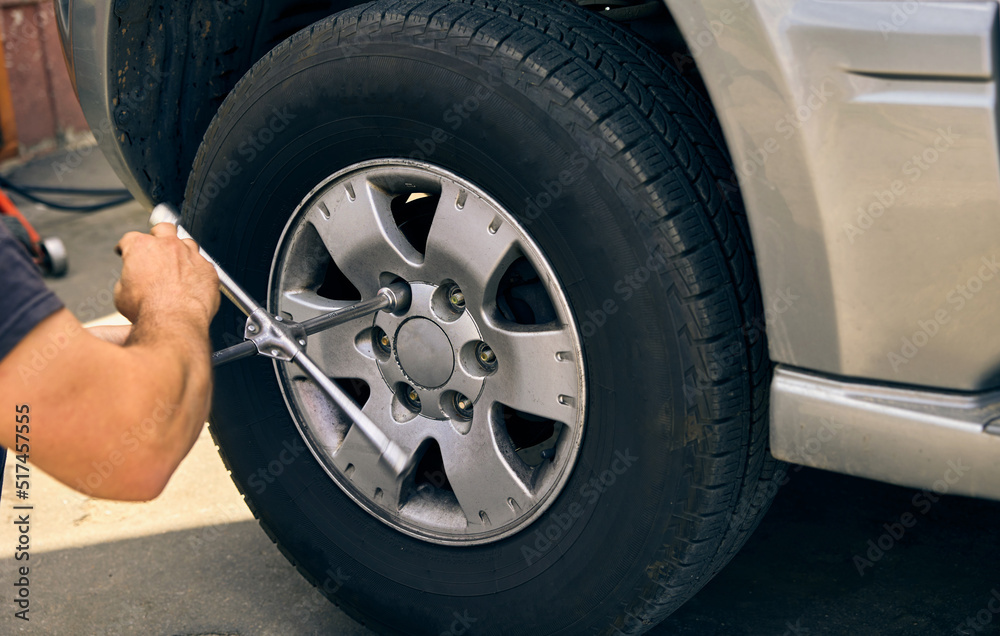 An unknown person dismantles a damaged car wheel for service An unknown person dismantles a damaged car wheel for service