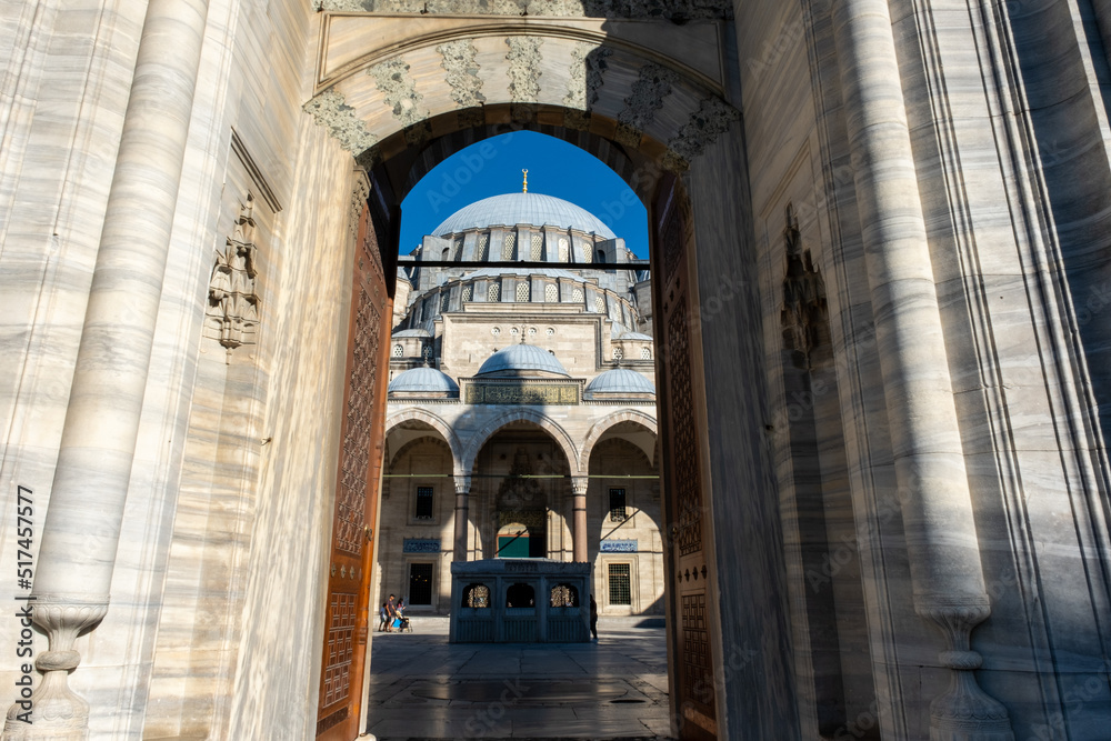 Suleymaniye Mosque entrance and dome view with a blue sky, old ancient structure, beautiful landmarks with mosque gate, Muslim and Islam concept: Suleymaniye Mosque, Istanbul, Turkey - June 25 2022