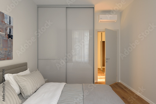 wardrobe with glass facades in the bedroom, interior of a bedroom, modern bedroom in beige tones