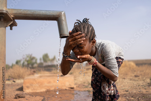 Fototapeta Little African girl cooling her forehead and face on a scorching hot day at the
