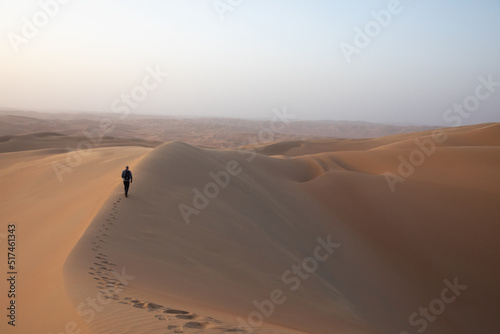 Man with a camera and backpack in desert at sunrise.