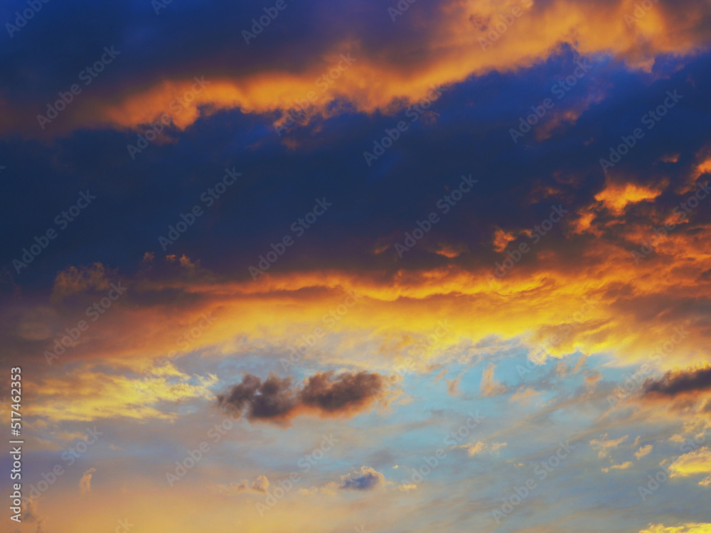 Cloudy sky at sunset. Dark blue and yellow natural background or wallpaper. The rays of the setting sun effectively illuminate the clouds. Beautiful and dramatic evening skies. Twilight cloudscape