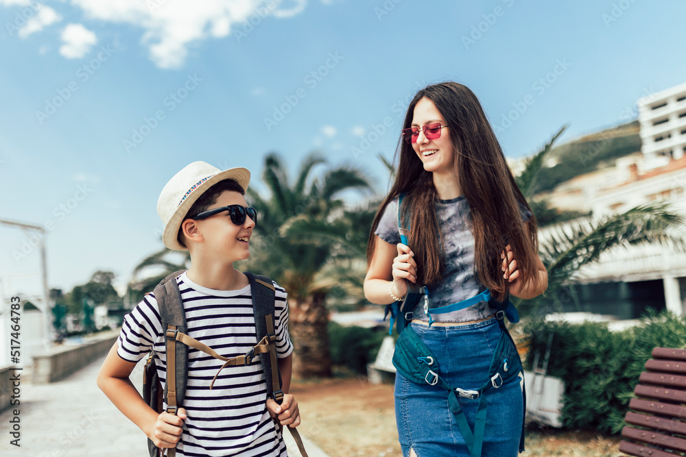 Brother and sister walking together at seaside with luggage backpack. Travel, tourism, family concept. Brother and sister walking together at seaside with luggage backpack. Travel, tourism, family concept.