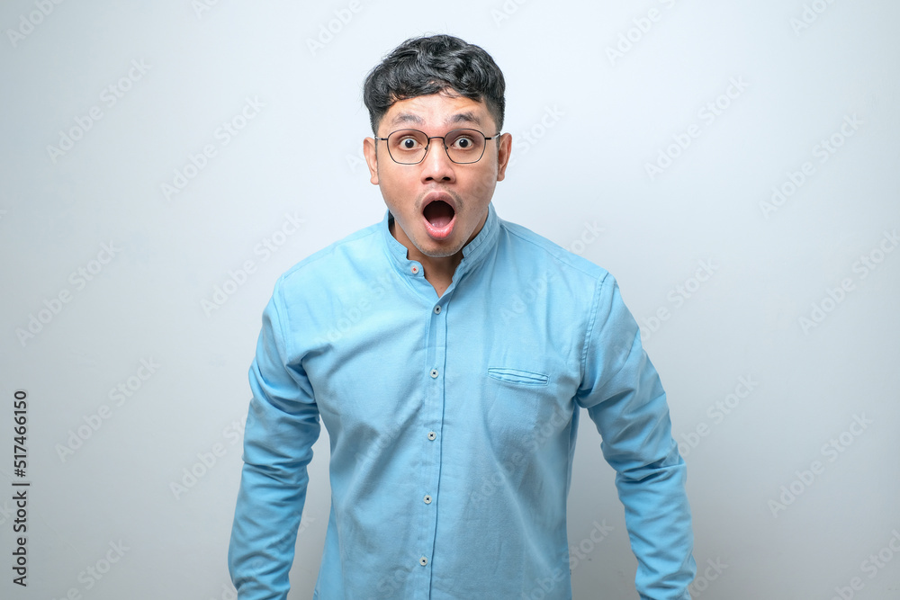 Amazed asian young man with open mouth and bulging eyes looking at camera