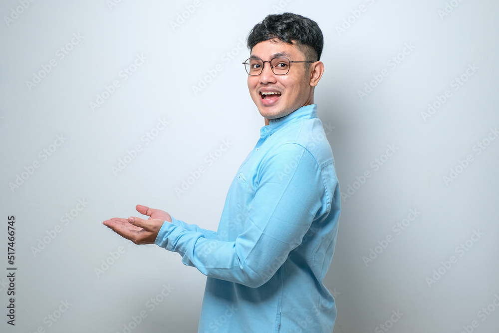 Young handsome asian man with a big smile on face, pointing with hand finger to the side looking at the camera. Young handsome asian man with a big smile on face, pointing with hand finger to the side looking at the camera.