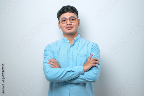 Asian man standing with arms crossed and smiling at camera isolated over white background photo