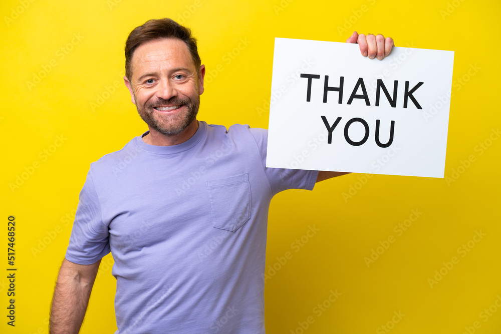 Middle age caucasian man isolated on yellow background holding a placard with text THANK YOU with happy expression Middle age caucasian man isolated on yellow background holding a placard with text THANK YOU with happy expression
