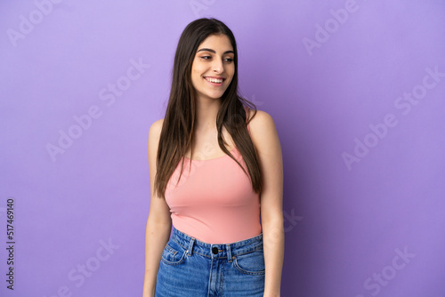 Young caucasian woman isolated on purple background looking side