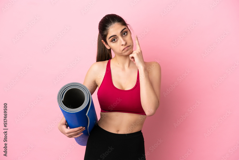 Young sport caucasian woman going to yoga classes while holding a mat thinking an idea Young sport caucasian woman going to yoga classes while holding a mat thinking an idea