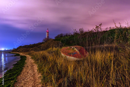 Boat on the beach at night. Lighthouse in the back. Beautiful landscape. photo