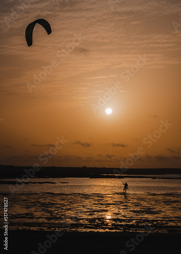 Kite surfing around the cotillo beach lighthouse in a sunset
