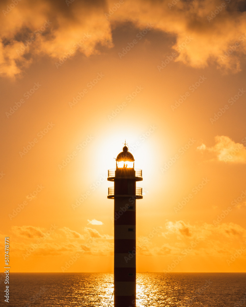 lighthouse with the sun behind illuminating the sea