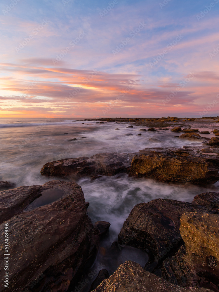 Colorful sunrise view at rocky coastline.