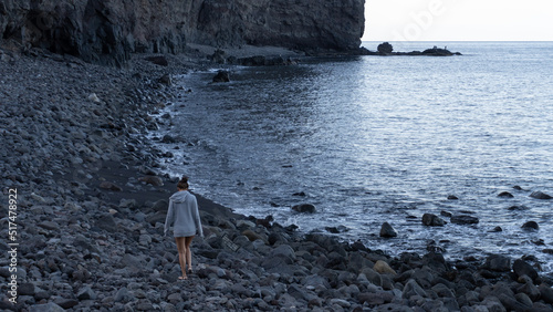 Young girl walking along the pebble beach of Tasartico, on the island of Gran Canaria