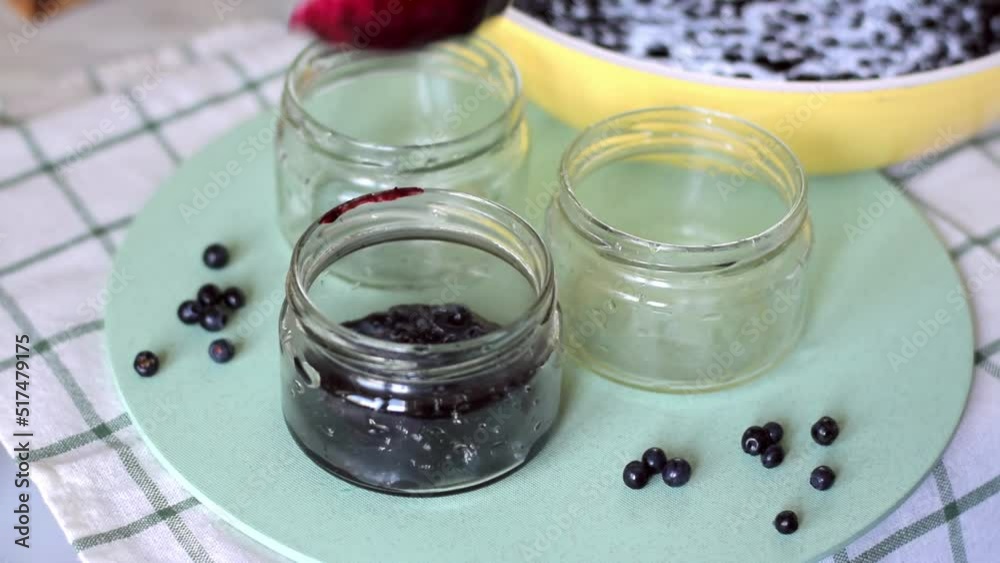 Pouring homemade bilberry or blueberry jam (confiture) into glass jars. Canning and preserving berry dessert Pouring homemade bilberry or blueberry jam (confiture) into glass jars. Canning and preserving berry dessert