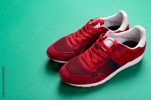 New unbranded running sneaker or trainer on green background. Men's sport footwear. Pair of sport shoes. © alexshyripa