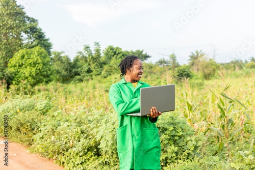 black Female farm agronomist checking an agricultural field using laptop