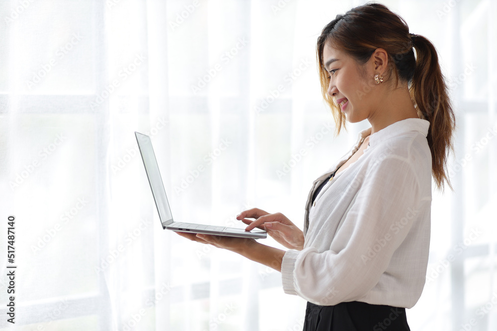 Portrait of a charming Asian businesswoman standing with a laptop. Portrait of a charming Asian businesswoman standing with a laptop.