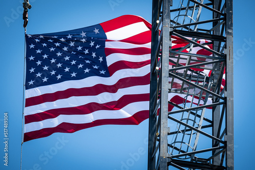 A construction site crane flying a United States Flag in the background with a clear blue sky on a bright sunny day