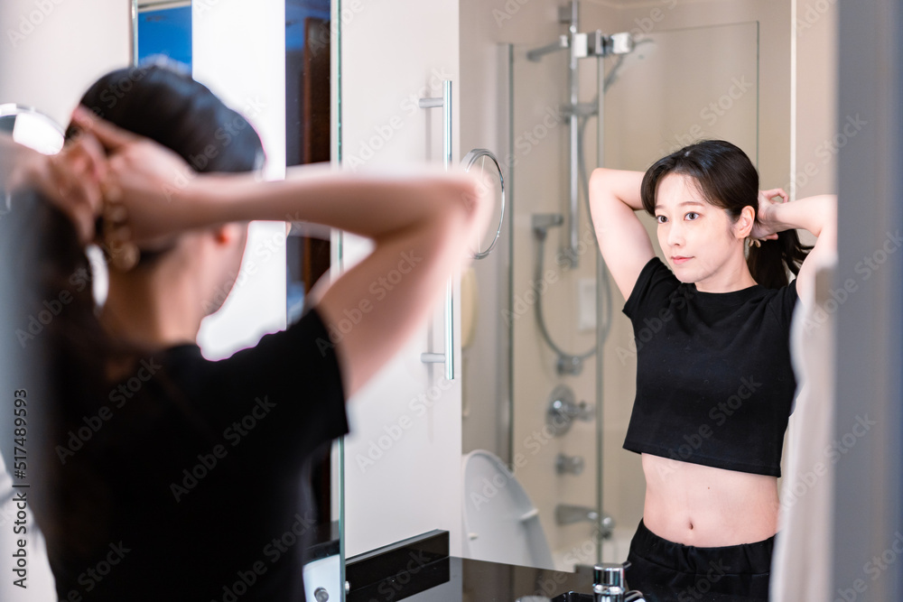 鏡の前で髪のセットをする若い女性 鏡の前で髪のセットをする若い女性